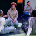 Students sit on mats on the ground in a circle and talk.