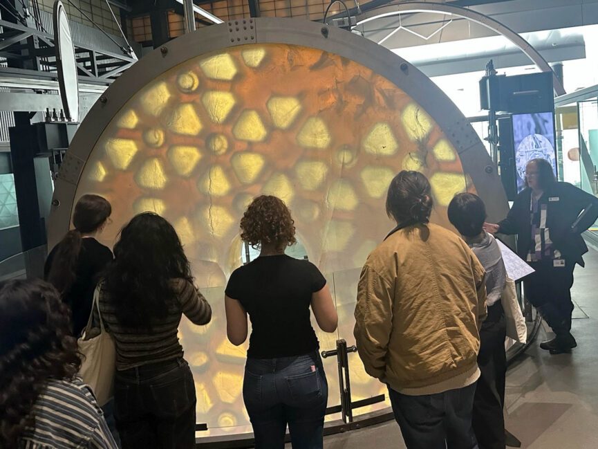 People look at a large circular structure.