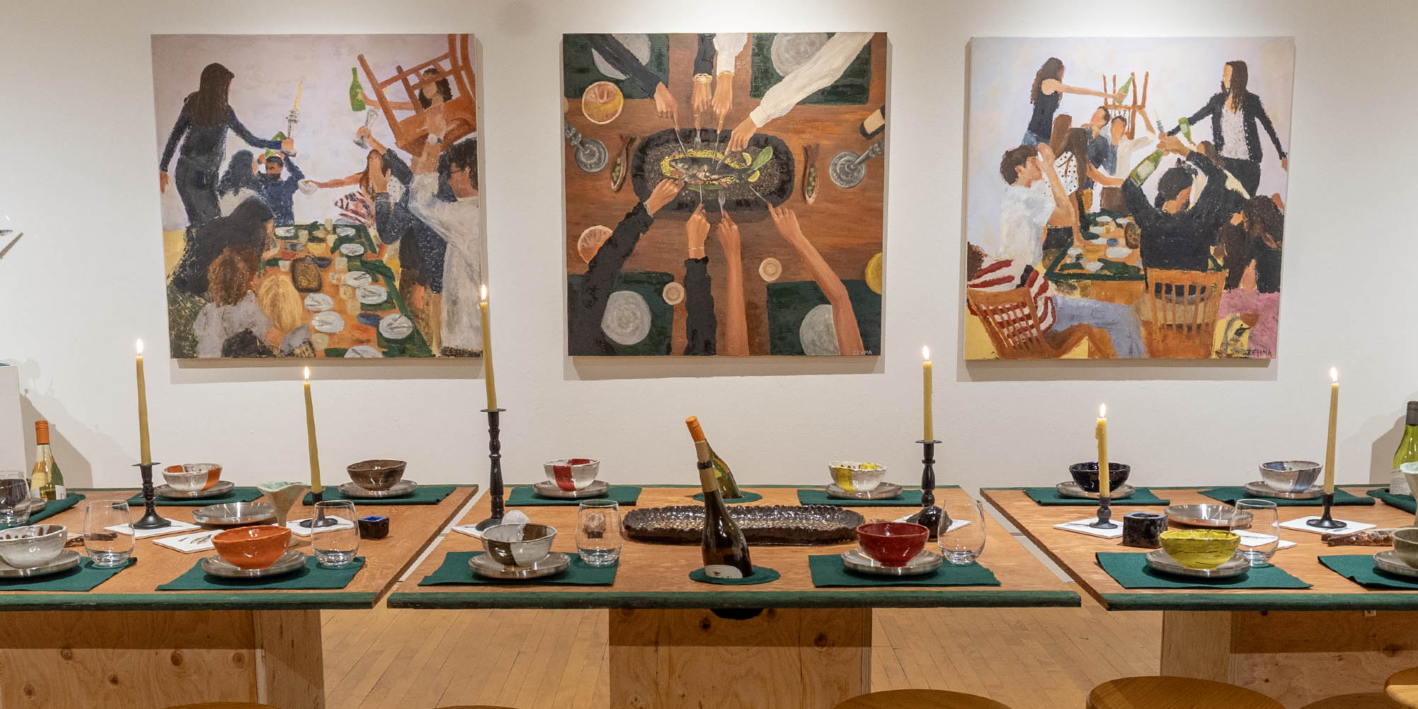 An ornately set table is on view in front of painting on a wall of a gallery.