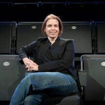 Portrait of Tess James sitting in a row of empty theater seats.