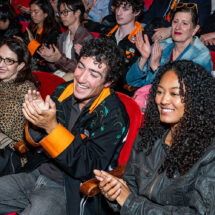 A crowd of people applaud in an auditorium.