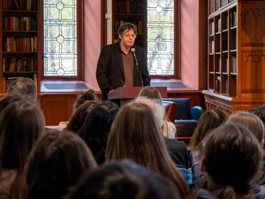 A person reads into a microphone at a podium.