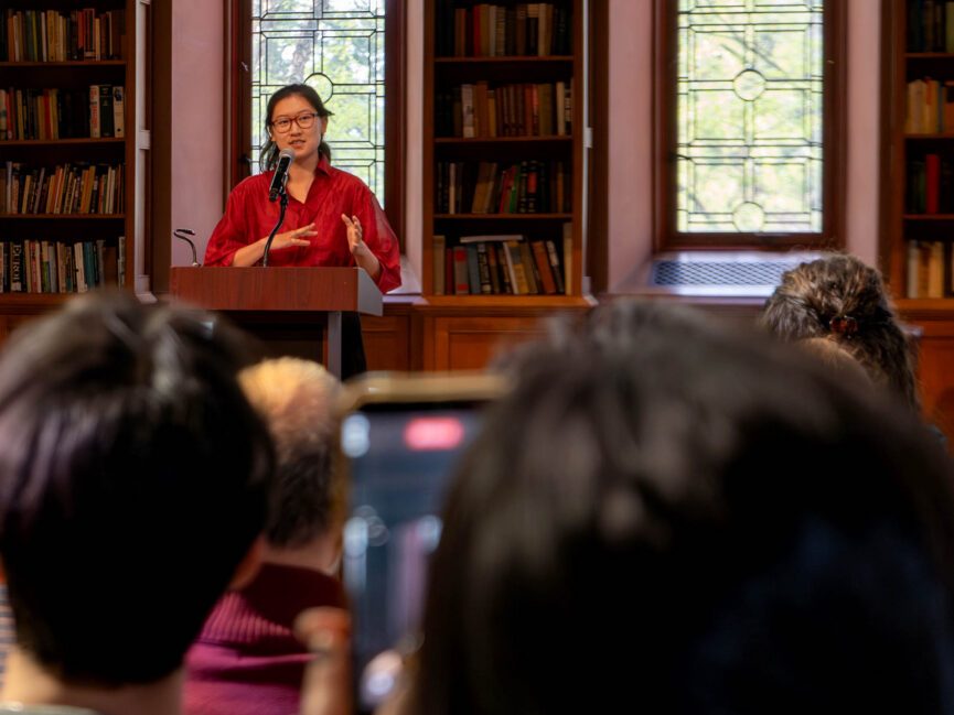 A person gestures as she reads from a podium.