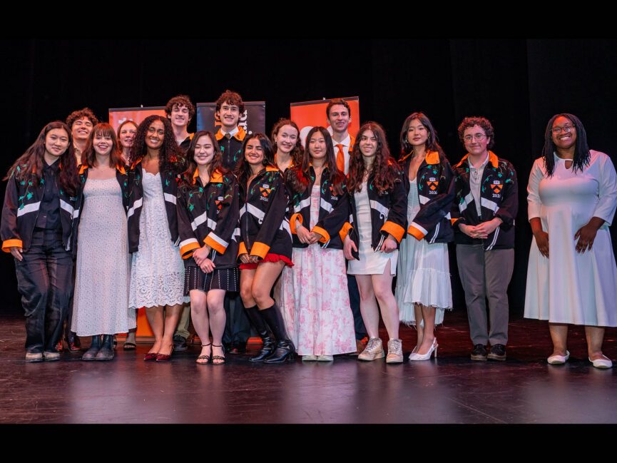 A large group of students pose for a photo on a stage.