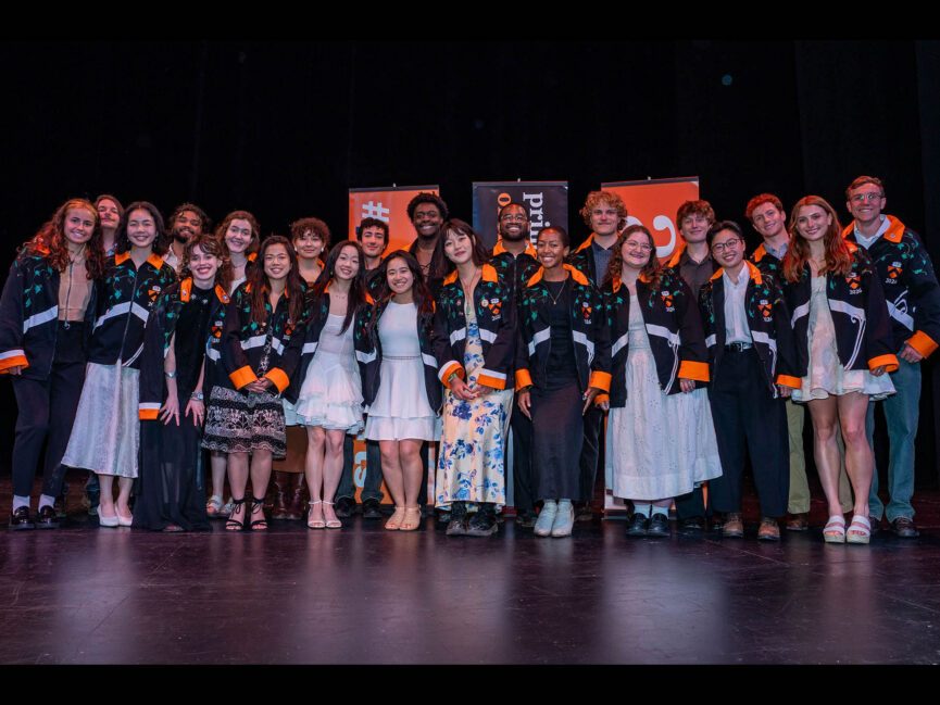 A large group of students pose for a photo on a stage.