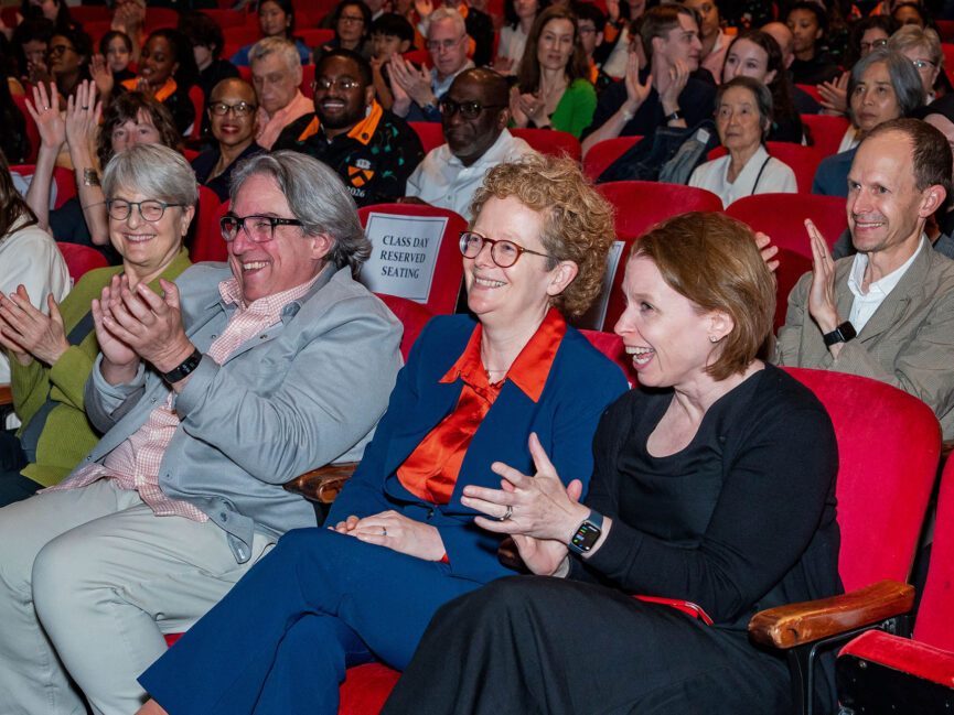 A crowd of people applaud in an auditorium.