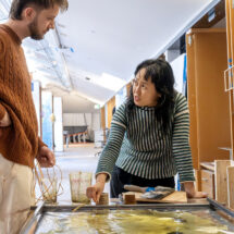 Two people work together on artwork in a studio setting